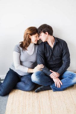 İlişkiler, duygular, rahatlama konsepti. Yerde hasır kürkle kaplanmış bir çift sevgili var, toplumun yeni bir birimi, yeni doğmuş bir aile, bebeği bekliyor.