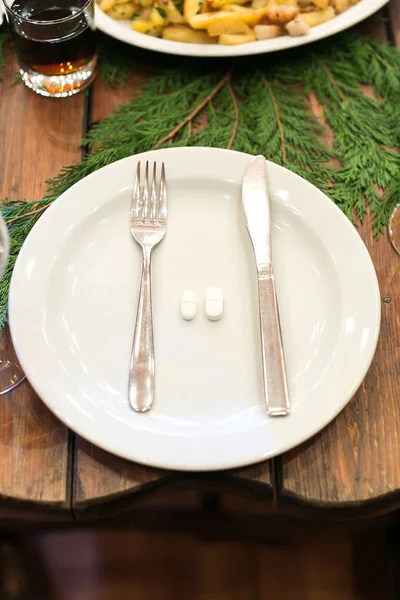 装飾パーティー医学の概念 銀器や丸薬のついた白い皿の上からは スプルースの枝で飾られた木のテーブルの上に置かれている — ストック写真
