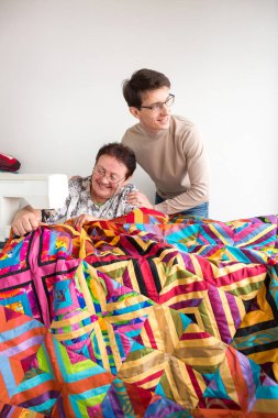 sanat, zanaat, mutluluk konsepti. Hafif atölyede iki kişi var, dikiş makinesiyle çalışan yaşlı bir terzi ve harika bir yorgan yapma sürecini kontrol eden genç bir tasarımcı.