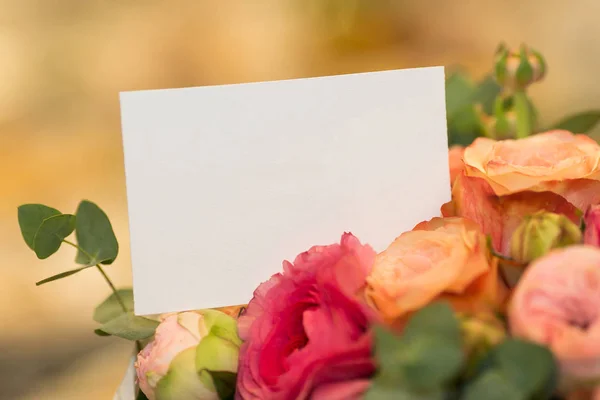 Heilwens, natuur, concept vakantie. Close-up van schone witte wenskaart dat wordt geplaatst onder prachtige bloemen, er zijn rozen van roze, licht oranje en rode kleuren — Stockfoto