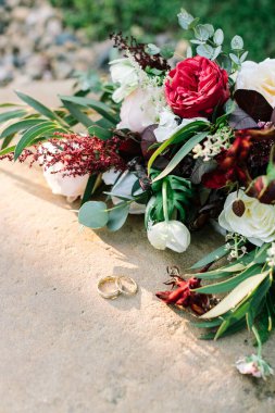 Aksesuarlar, düğün malzemeleri konsepti. Nikah yüzüklerini ve düğün buketini yakın plan çek..