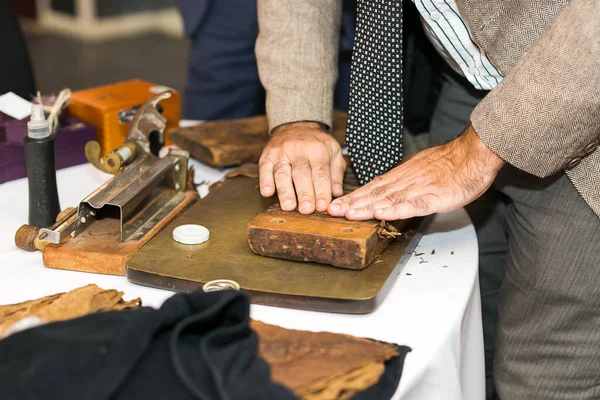 The moment of making an extra class cigar with the help of traditional Cuban production tools. measuring the length and thickness of the cigar with the help of cepo