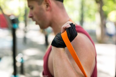 Spor sahasında spor yapan elastik bantla çalışan konsantre atletik adamın yan görünüşü