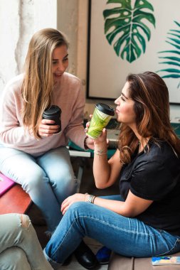 Kafede kahve içen kadınlarla sohbet etmek. Genç kızlar kahvelerini içerken kahve içip rahatlıyorlar.