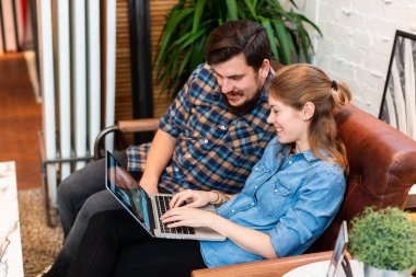 Kanepede dizüstü bilgisayar izleyen rahat bir çift. Keyifli kadın ve erkek kanepede takılıyor ve laptopu mutlu bir şekilde paylaşıyor.