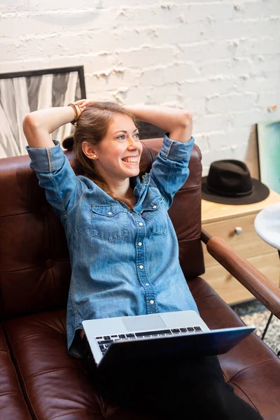 Relaxed cheerful woman with laptop on sofa