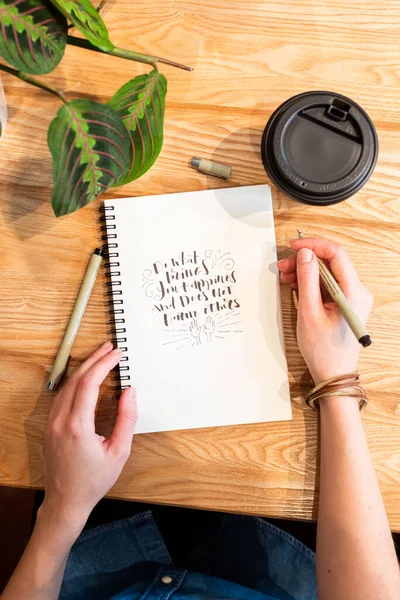 Кукурудза жінка малює в блокноті і має каву за лічильником — стокове фото