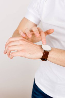 Kesilmiş dikey çerçeve - beyaz arka plandaki eller bir kol saatinin dokunmatik ekranıyla etkileşime girer. Artırılmış gerçeklikle çalışma kavramı. 