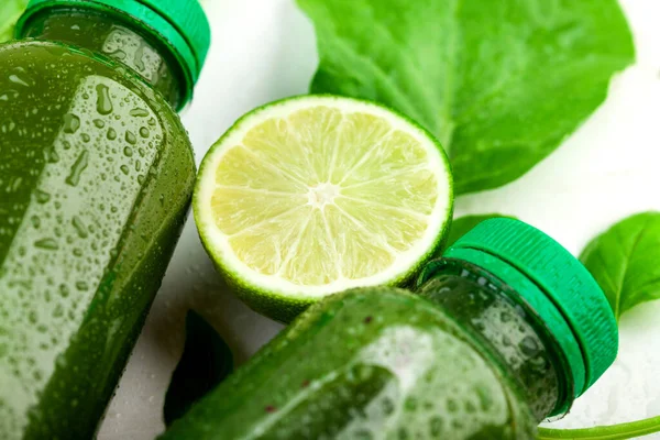 关闭石灰片之间的瓶子绿色饮料白色背风 为健康饮食创造清爽饮料的概念 — 图库照片