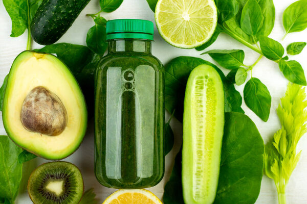 Close-up, a view from above on a freshly squeezed green detox drink and a set of vegetables used to create it. The concept of fresh, tasty low-calorie smoothie