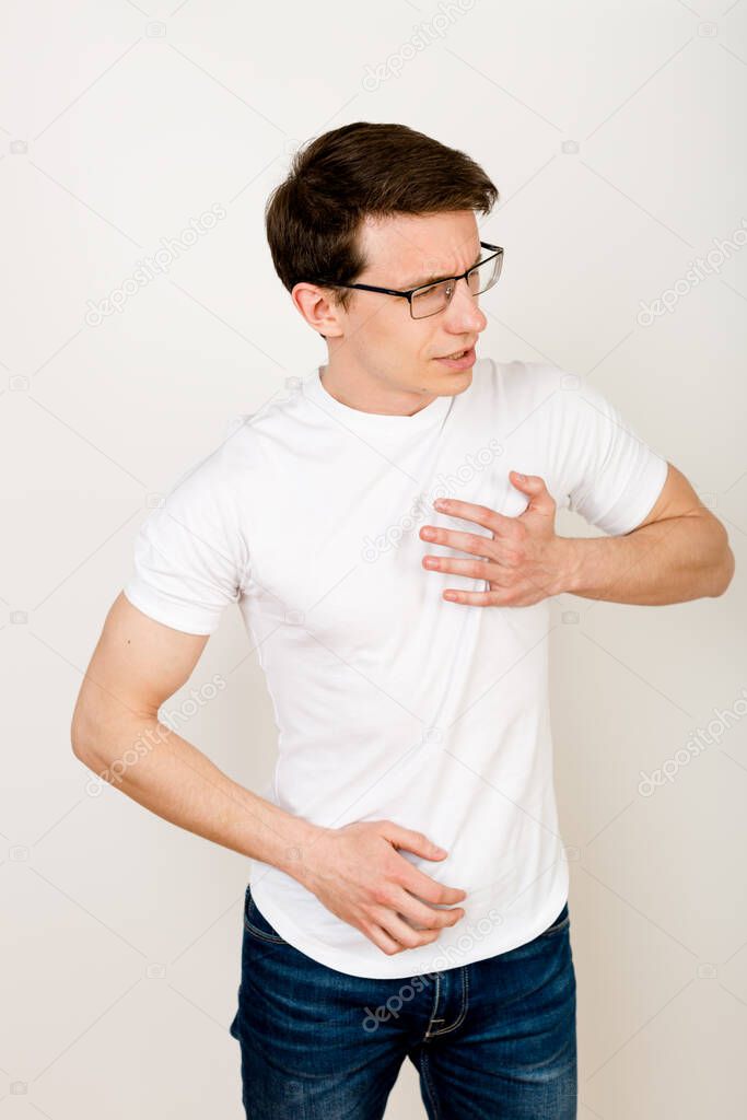 Man holding his chestwith his hands The concept of physical pain, body disorders. The harm of constant work with the computer, sedentary lifestyle. Damage to health from unhealthy life and habits.