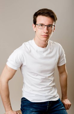 Her gün monoton giyinen genç bir adam beyaz arka planda oturur ve yüzünde ciddi bir ifadeyle doğrudan kameraya bakar..