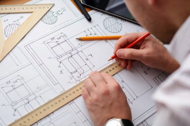 Makine Mühendisi iş başında. Teknik çizimler. Teknik çizimler ve diyagramlar ile kağıt.