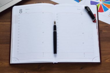 Mali yazdırılan kağıt çizelgeleri, grafikler, diyagramlar ve ahşap bir masa üstünde defter