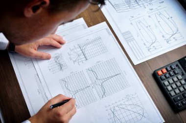 Makine Mühendisi iş başında. Teknik çizimler. Teknik çizimler ve diyagramlar ile kağıt.