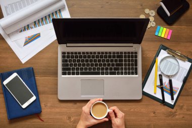 Finansal veriler analiz ediliyor ve bilgisayara güveniliyor. Bir bilgisayarın klavyesinde çalışan erkek eller. Elinde bir fincan kahveyle ara ver.