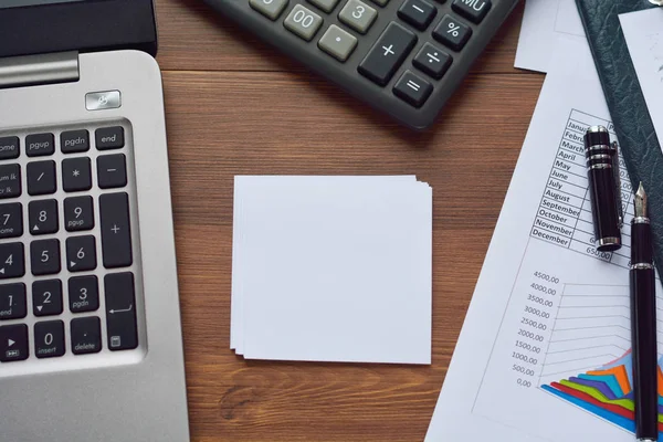 Cuadros financieros impresos en papel, gráficos, diagramas, computadoras, bolígrafos y calculadoras en un escritorio de madera . — Foto de Stock