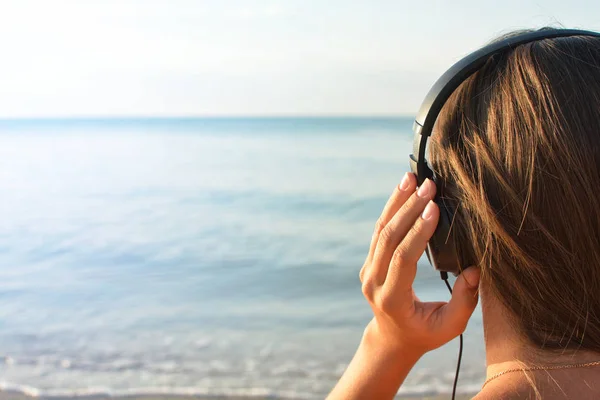 Junge Frau mit Kopfhörer Musik hören und genießen schöne Aussicht Meer, Rückansicht. — Stockfoto