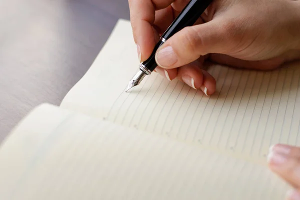 Caligrafía, mano escribe un bolígrafo en un cuaderno. Macro con desenfoque y enfoque suave . — Foto de Stock