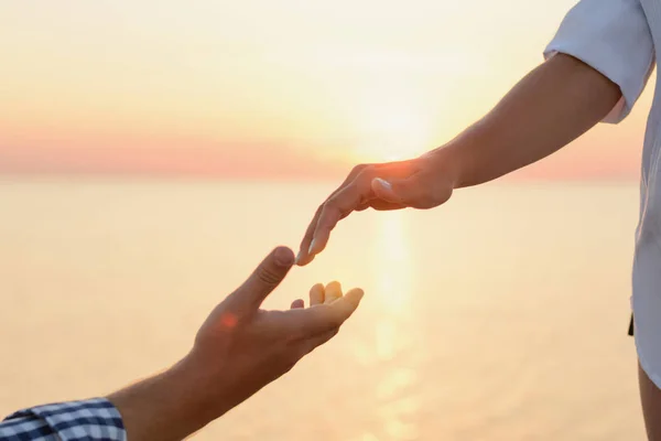 Lover boy makes an offer to his deushke on beach at sunrise (dawn). Creating a family. Creating a family. hands of the bride and groom on the background of sea close-up. Hand of support and help.