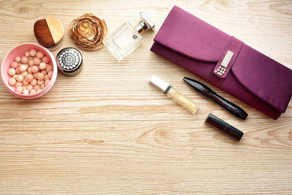 косметика (крем, лак для ногтей, тени для век, брови, помада, блеск для губ, румяна, порошок и духи) на деревянном столе
 