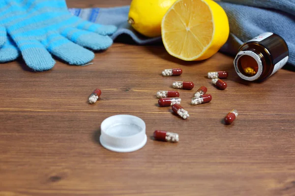 Meleg ruházat, tea citrommal és tabletták az asztalon. — Stock Fotó