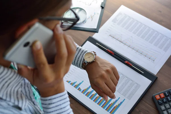 Empresaria habla por teléfono, discutiendo los gráficos de ganancias de la compañía con la gerencia — Foto de Stock