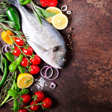 Taze çiğ balık, dorado, çipura limon, otlar, sebzeler ve baharat rustik arka plan üzerinde. Üstten Görünüm. Metniniz için boş alan
