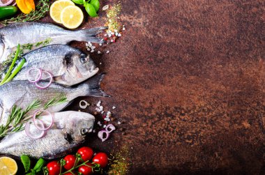 Taze çiğ balık, dorado, çipura limon, otlar, sebzeler ve baharat rustik arka plan üzerinde. Üstten Görünüm.