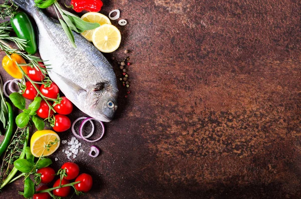 Frischer roher Fisch, Dorado, Dorade mit Zitrone, Kräutern, Gemüse und Gewürzen auf rustikalem Hintergrund. Ansicht von oben. Freiraum für Ihren Text — Stockfoto