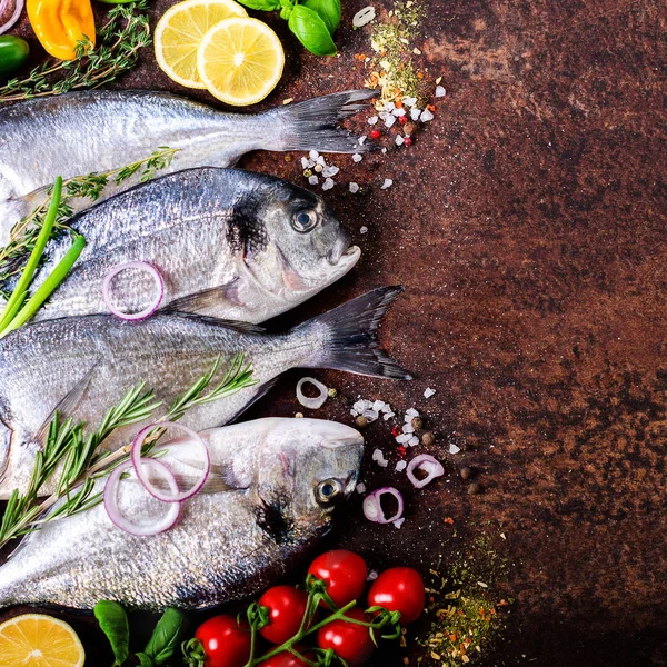 Dorada, fresh fish with vegetable, lemon, herbs, onion, paprika, cherry tomatoes, onion, salton dark vintage background. Copy space.