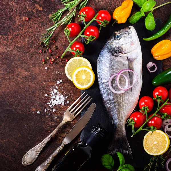 Peixe fresco não cozido, dorado, dourado com limão, ervas, legumes e especiarias em fundo rústico. Vista superior . — Fotografia de Stock