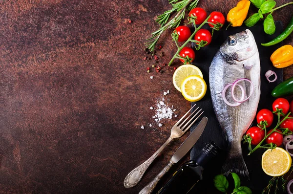 Dorada, peixe fresco com vegetais, limão, ervas, cebola, páprica, tomate cereja, cebola, saltão fundo escuro vintage. Espaço de cópia . — Fotografia de Stock