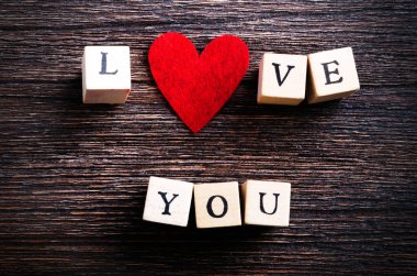 Ahşap küpleri yazıt ile ahşap arka plan üzerinde kırmızı Tekstil kalp seviyorum. Metniniz için boş alan.