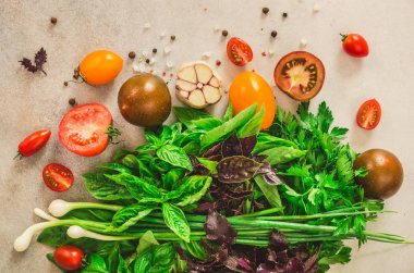 Taze ıspanak, yeşil soğan, fesleğen, otlar, dereotu ve seçici odak gri beton zemin üzerine domates. Üstten Görünüm. Tonda etkisi. Malzemeler Food yemek. Vegan, ham, detoks kavramı
