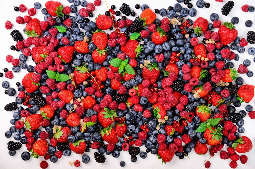 Assortment of strawberry, blueberry, currant, mint leaves. Summer berries background with copy space for your text. Top view. Food frame and border design. Vegan, vegetarian concept.