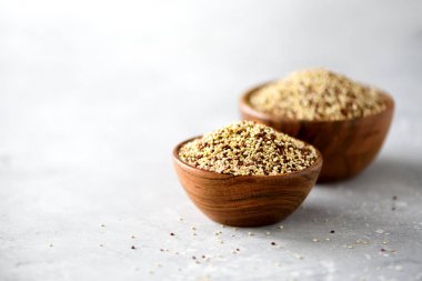 Beyaz ve kırmızı ham organik quinoa ahşap kase ve biberiye gri arka plan üzerinde. Sağlıklı gıda maddeleri. Kopya alanı