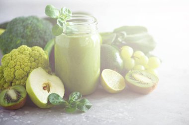 Yeşil sağlık güler yüzlü, lahana yaprakları, limon, elma, kivi, üzüm, muz, avokado, marul ile Cam Kavanoz kupalar. Uzay kopyalayın. RAW, vegan, vejetaryen, alkalin gıda kavramı. Afiş