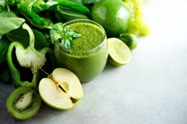 Yeşil sağlık güler yüzlü, lahana yaprakları, limon, elma, kivi, üzüm, muz, avokado, marul bardak. Uzay kopyalayın. RAW, vegan, vejetaryen, alkalin gıda kavramı.