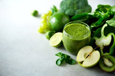 Yeşil sağlık güler yüzlü, lahana yaprakları, limon, elma, kivi, üzüm, muz, avokado, marul bardak. Uzay kopyalayın. RAW, vegan, vejetaryen, alkalin gıda kavramı.