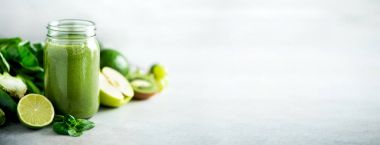 Yeşil sağlık güler yüzlü, lahana yaprakları, limon, elma, kivi, üzüm, muz, avokado, marul ile Cam Kavanoz kupalar. Uzay kopyalayın. RAW, vegan, vejetaryen, alkalin gıda kavramı. Afiş