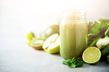 Yeşil sağlık güler yüzlü, lahana yaprakları, limon, elma, kivi, üzüm, muz, avokado, marul ile Cam Kavanoz kupalar. Alanı, güneş ışığı etkisi kopyalayın. RAW, vegan, vejetaryen, Detoks, alkalin gıda kavramı.