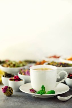 Çay kavramı kopya alanı ile. Kuru çay beyaz seramik kaseler ve gri arka plan üzerinde aromatik çay çeşitleri.