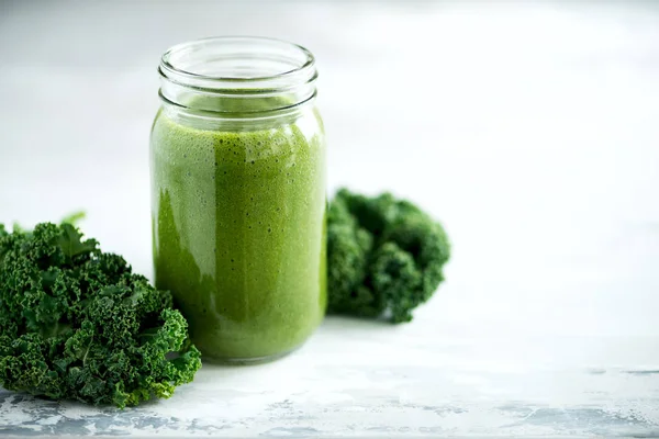 Glass jar mugs with green health smoothie, kale leaves, lime, apple, kiwi, grapes, banana, avocado, lettuce. Copy space, sunlight effect. Raw, vegan, vegetarian, detox, alkaline food concept. — Stock Photo, Image