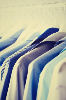 Erkek giyimi, ceket ve gömlek elbise demiryolu üzerinde asılı. Mavi renk giysiler. Uzay kopyalayın. Görüntü tonda etkisi ile