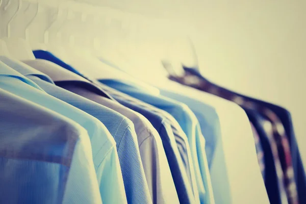 Мужская одежда, куртки и рубашки, висящие на перилах одежды. Синий цвет одежды. Принято. Изображение с тонированным эффектом — стоковое фото