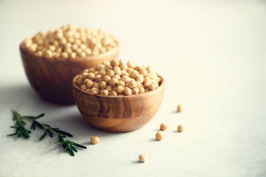 Ahşap kase ve biberiye gri beton zemin üzerine organik çiğ nohut. Sağlıklı gıda maddeleri. Uzay kopyalayın. Afiş