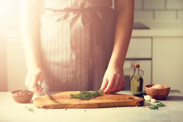 Manos de mujer cortando romero verde fresco sobre tabla de cortar de madera en la cocina blanca, interior. Copiar espacio. Comida casera engreída, receta saludable. Llévame a trabajar. — Foto de Stock
