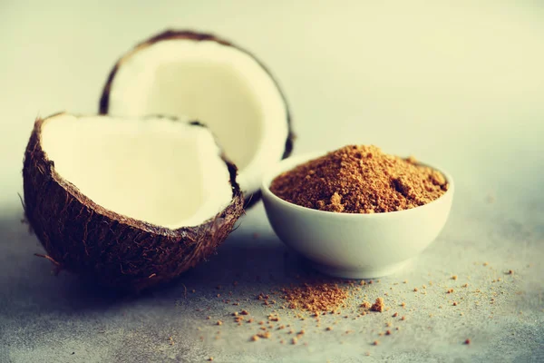 Kokospalmen brauner Zucker und die Hälfte der Kokosfrüchte auf grauem Betongrund. Kopierraum — Stockfoto