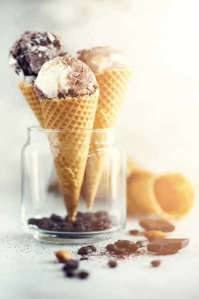 Chocolate and coffee ice cream in waffle cone with coffee beans on grey stone background. Summer food concept, copy space. Healthy gluten free ice-cream. Banner